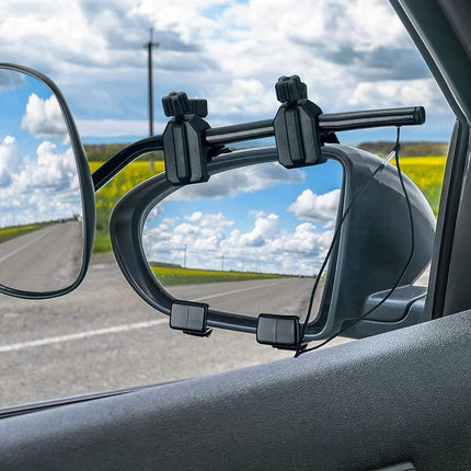A black car-mounted side mirror accessory attached to the passenger-side window, shown in use with a road and cloudy sky visible in the mirror reflections.