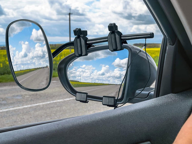 A black car-mounted side mirror accessory attached to the passenger-side window, shown in use with a road and cloudy sky visible in the mirror reflections.