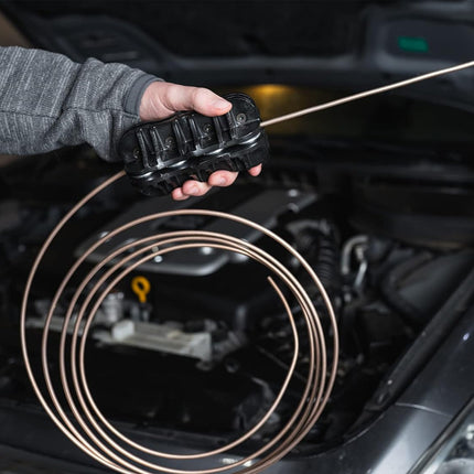 Person holding a coiled diagnostic cable in front of an open car hood.