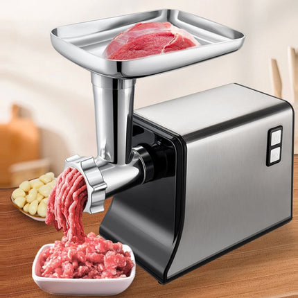 Meat grinder in action on a wooden table with ground meat and ingredients.