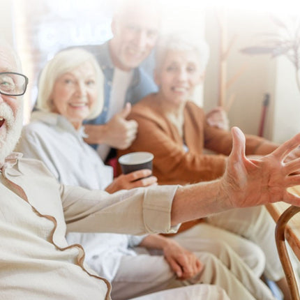 Group of elderly people sitting together, one person using a smartphone.