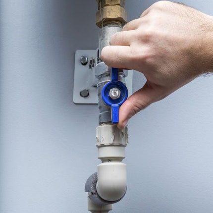 Hand adjusting a blue valve on a plumbing system against a gray background