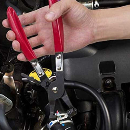 A close-up of a person's hand using red-handled metal wire stripping pliers on a black hose in an engine bay.