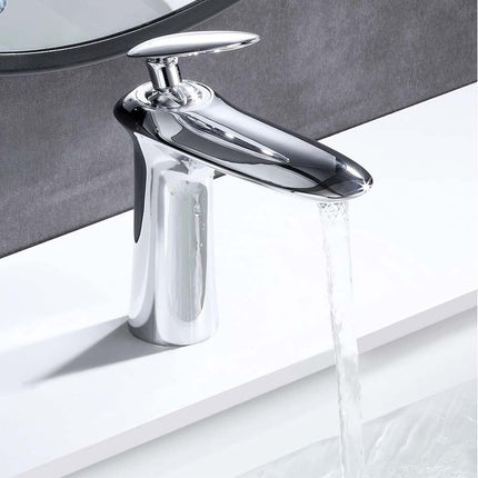 A polished chrome single-handle bathroom faucet with water flowing from the spout, mounted on a white sink against a dark gray wall.