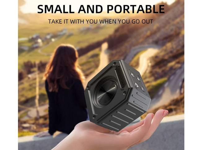 Hand holding a small black speaker with scenic background