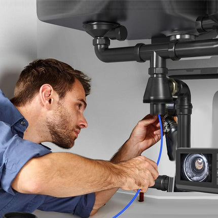 Plumber using a camera to inspect pipes under a sink.