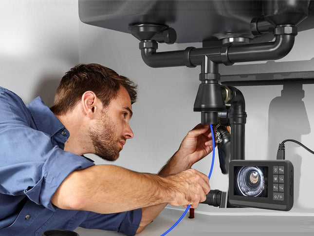 Plumber using a camera to inspect pipes under a sink.