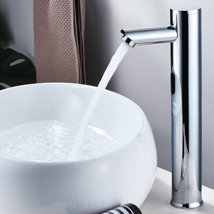A modern chrome waterfall bathroom faucet running into a white vessel sink, shown against a neutral gray background.