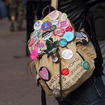 Beige backpack with various colorful stickers on a blurred background