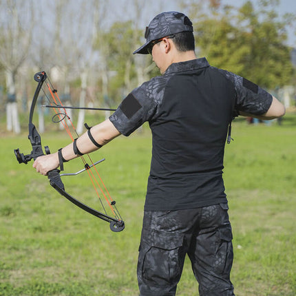 Person in camouflage clothing holding a bow and arrow outdoors on grass
