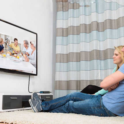 Couple sitting on a couch in a living room watching television.