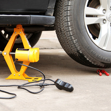 Yellow car jack under a vehicle on a concrete surface