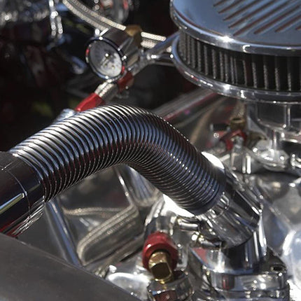 Close-up of a shiny engine with a hose and various components.