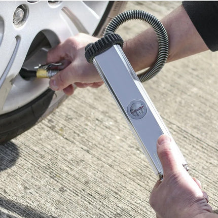 Person using a tire pressure gauge on a car tire.