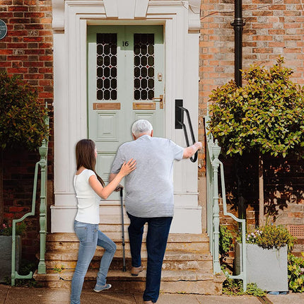Two people entering a house through a green door on a brick building.