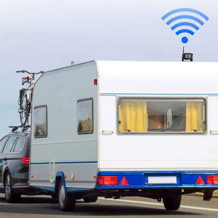 Car with a trailer and bicycle on a road with a clear sky