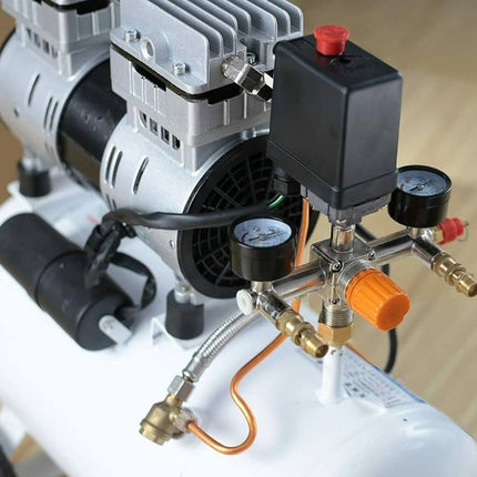 Close-up of a white air compressor with visible hoses and gauges on a wooden surface.