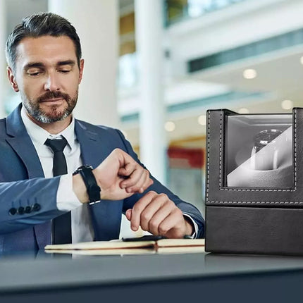 Man in a suit checking his watch next to a black watch box with a reflective surface.