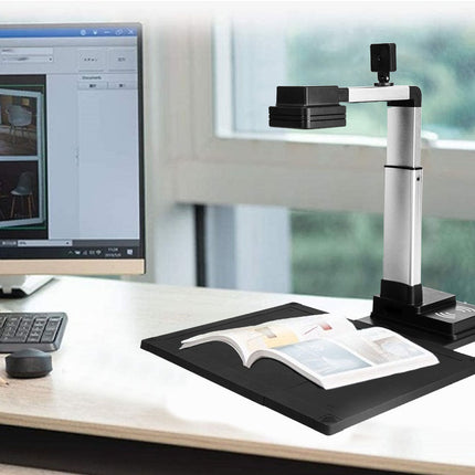 Book being scanned by a document camera on a desk with a computer monitor in the background.