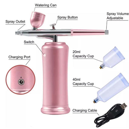 Pink air spray paint gun with labeled parts including watering can, spray button, spray volume adjustable, charging port, and two capacity cups (20ml and 40ml), plus a charging cable, on a white background.