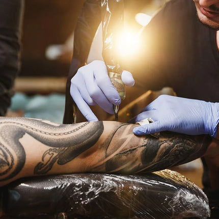 Person getting a tattoo with a tattoo artist applying ink.