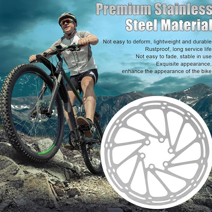 Man riding a bike on a mountain with a close-up of a stainless steel bike chainring.