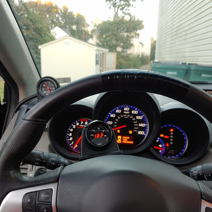 Car dashboard view from inside a vehicle with visible gauges and steering wheel.
