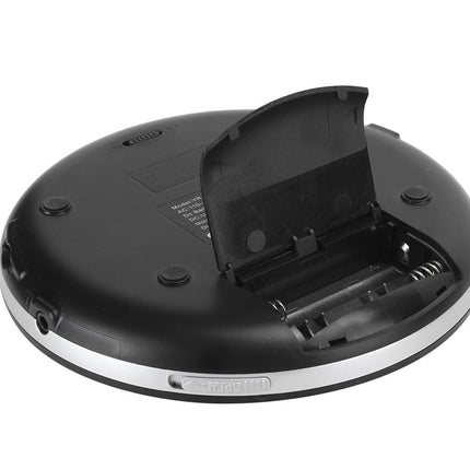 A black oval electronic device, shown from the bottom with its battery compartment lid open, revealing internal battery contacts and a spring. The device has a silver metallic band around the lower edge and is photographed on a solid white background.