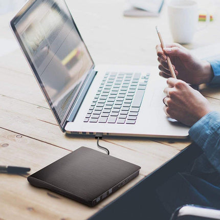 Person using a laptop with a pen on a wooden desk