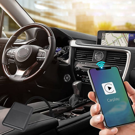 Car interior with smartphone displaying CarPlay on a screen, held by a hand.