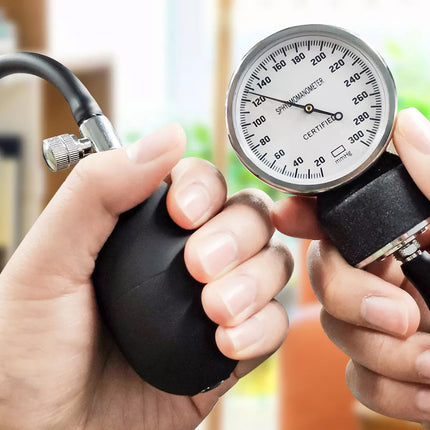 Hand holding a blood pressure monitor with a blurred background