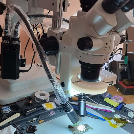 Microscope on a workbench with tools and components in a workshop setting