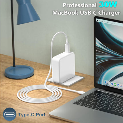 30W MacBook USB C Charger connected to a laptop on a desk with a lamp in the background.