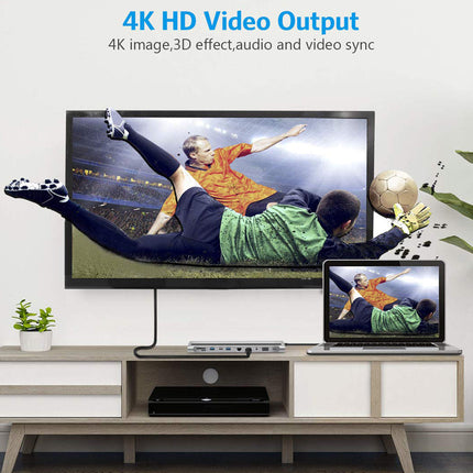 A 4K UHD television mounted above a media console, displaying a soccer scene with a large soccer ball. A laptop sits on the console to the right, showing the same image.