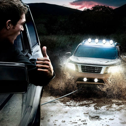Person in a vehicle giving a thumbs up to another vehicle driving through water on a dirt road.