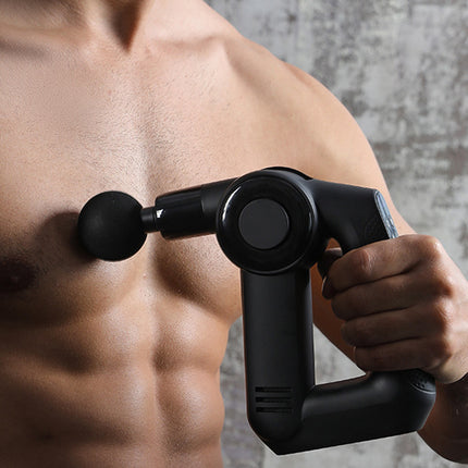 A close-up of a man's chest and hand holding a black handheld percussion massager against his pectoral muscle.