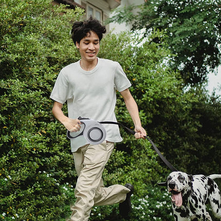 Person running with a dog on a leash in a garden