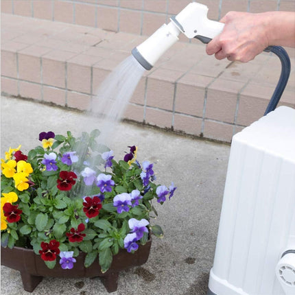Person watering a potted plant with a hose on a concrete surface.