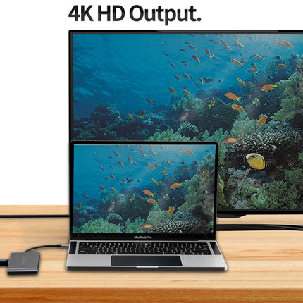 Laptop displaying an underwater scene with fish on a wooden surface, connected to a larger screen showing a similar scene.