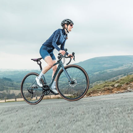 Person riding a bicycle on a road with a scenic background