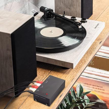 Turntable with vinyl record on a wooden turntable stand, surrounded by speakers and records.