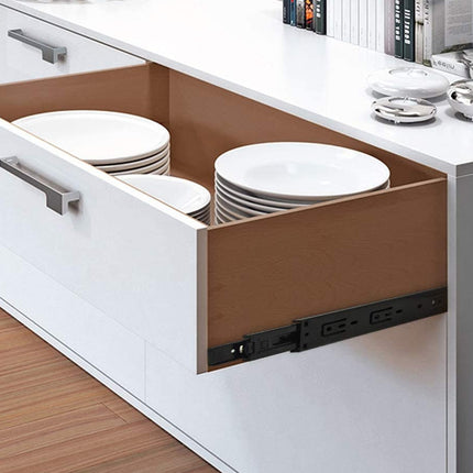 Open kitchen drawer with stack of plates inside, on a white countertop.
