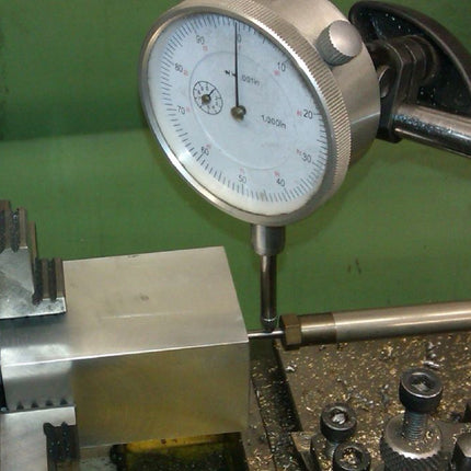 Mechanical measurement tool on a lathe with a green background