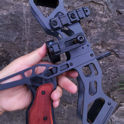 Hand holding a black crossbow with a blurred natural background