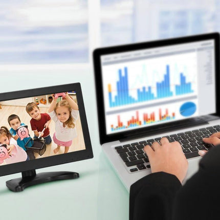 Person using a laptop with a screen displaying children playing, next to a smaller monitor showing a family.