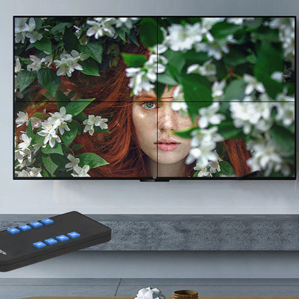 TV displaying a woman's face with greenery and flowers, remote control on the table.