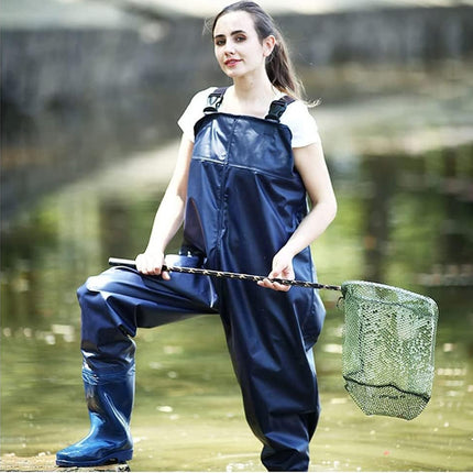 Woman in waders holding a fishing net by a body of water