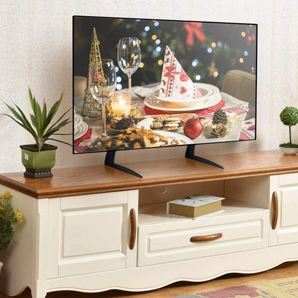 TV on a wooden stand with a festive scene displayed, surrounded by decorative plants and flowers.