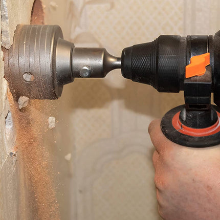 Person using a drill to remove a tile from a wall.