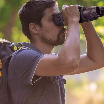 Man with a backpack using binoculars in a natural setting